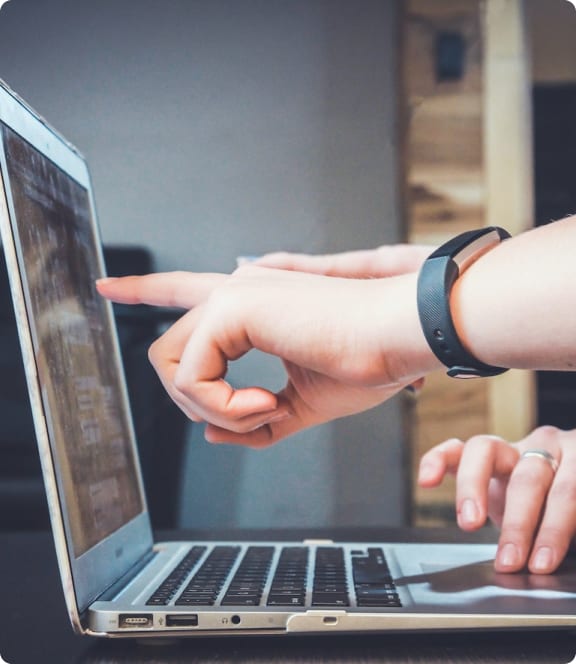Hand die iets aanwijst op het scherm van een laptop