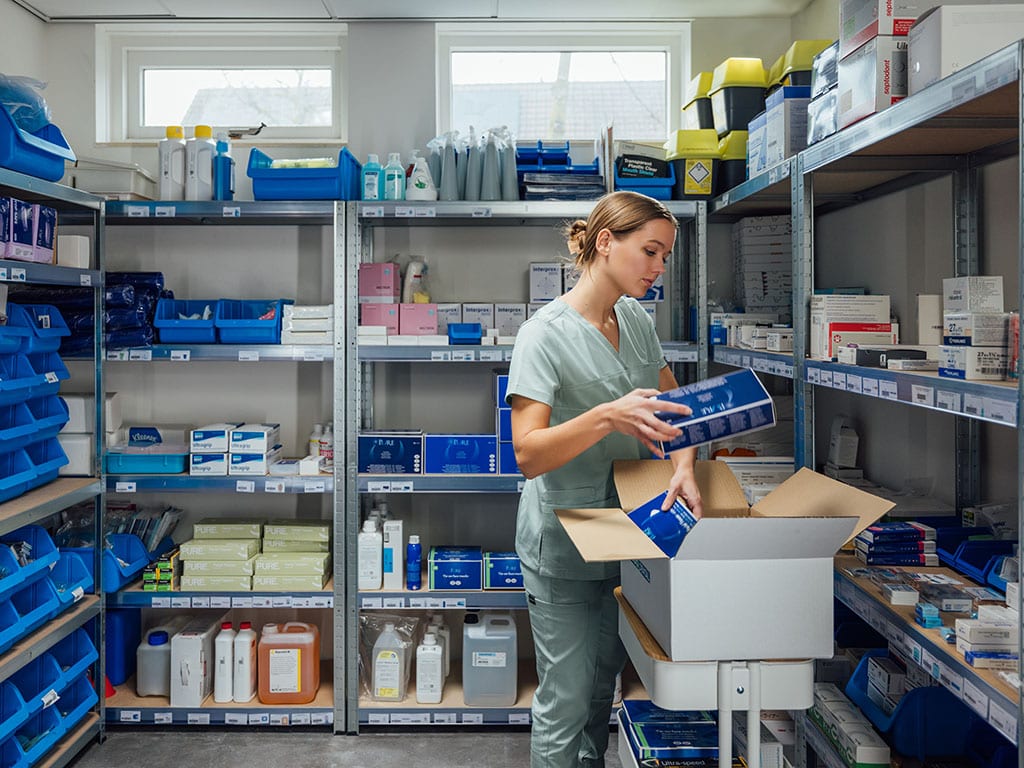 Tandartsassistente pakt een levering uit in het voorraadmagazijn van de praktijk