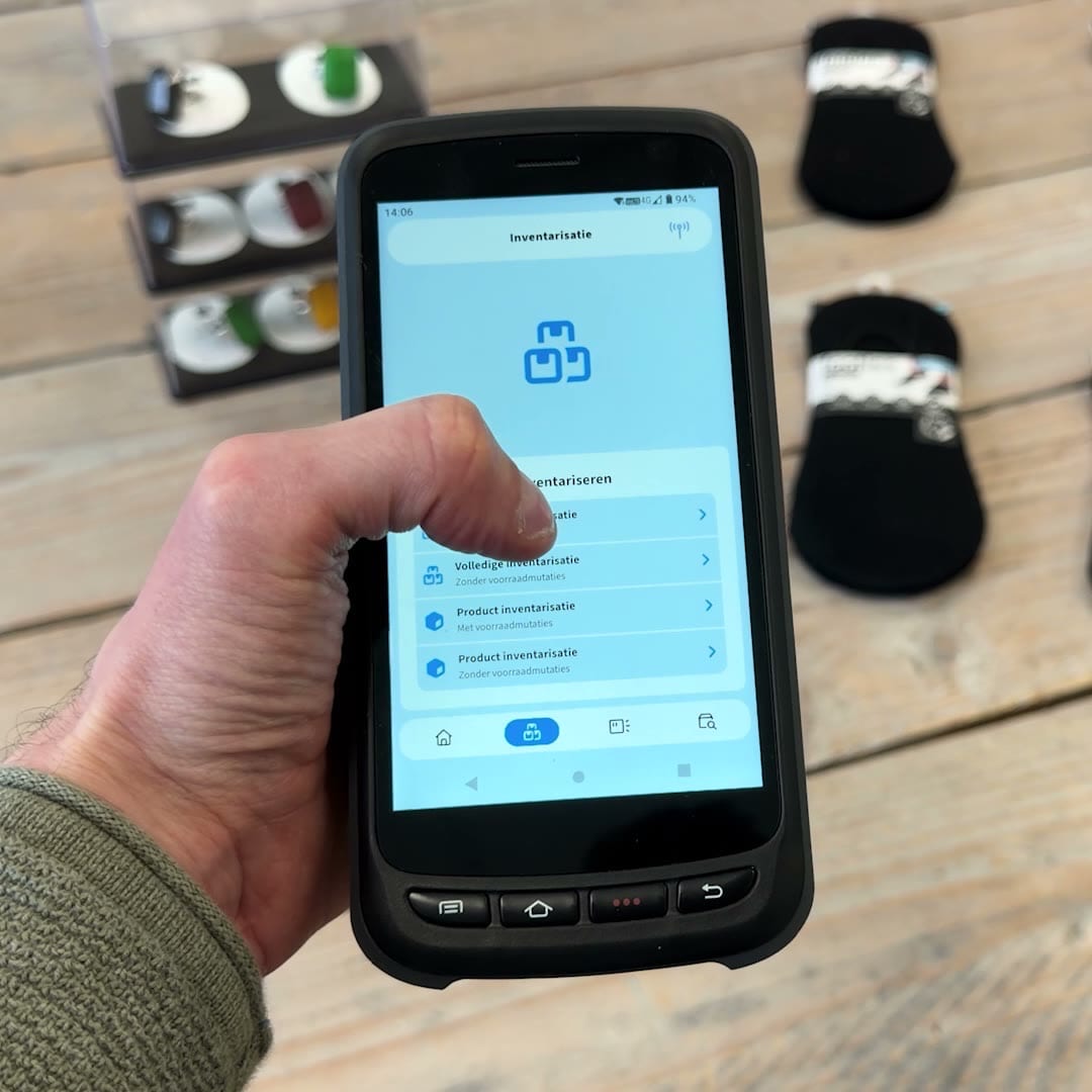 Medewerker inventariseert de voorraad in een magazijnstelling met een RFID-handheld