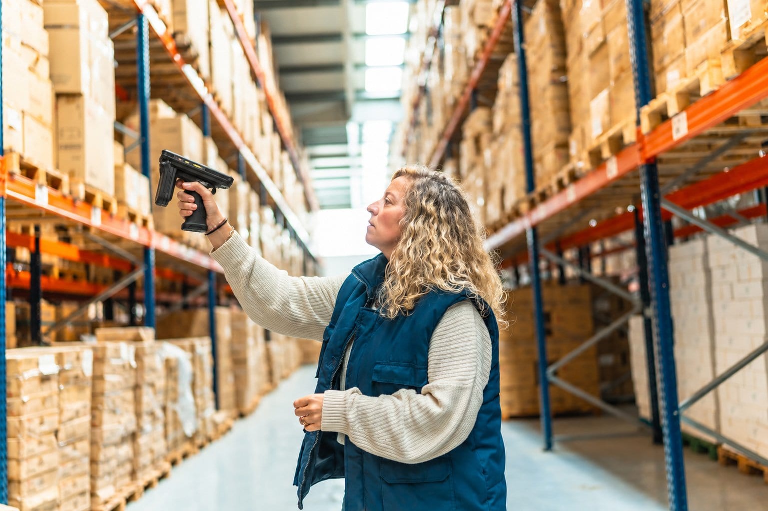 Een medewerker leest in een magazijn met een RFID-handheld de voorraad in de stelling uit